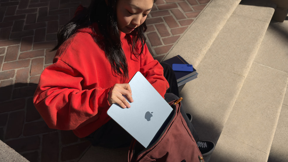 A Mac user slides MacBook Air into a backpack.